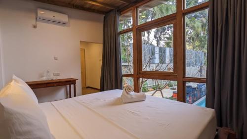 a bedroom with a bed and a large window at Barren House in Hiriketiya