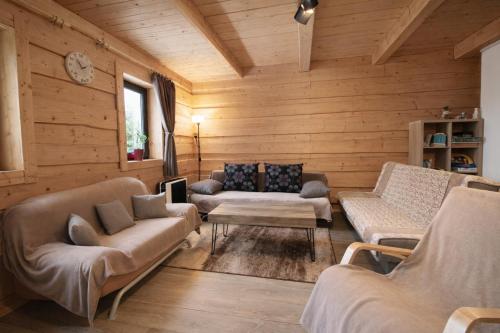a living room with wooden walls and couches at Chata pri Kaštieli - 2 E-bikes in Necpaly