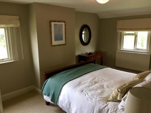 a bedroom with a large bed and two windows at The Old Three Pigeons in Nesscliffe