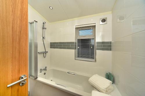 a bathroom with a bath tub and a shower at Finest Retreats - Heron Luxury Lodge in Bourn