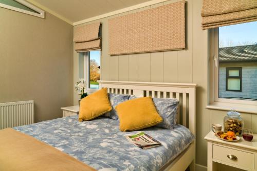 a bedroom with a bed with yellow pillows and a window at Finest Retreats - Heron Luxury Lodge in Bourn