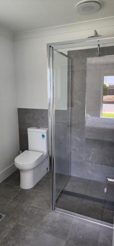 a bathroom with a toilet and a glass shower at Room In Dubbo With Queens Beds in Dubbo