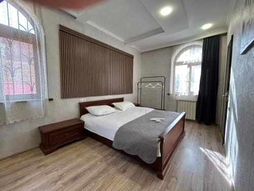 a bedroom with a bed and two windows at GuestHouse Old Avlabari in Tbilisi City