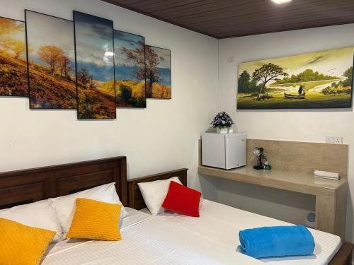 a bedroom with a bed with five paintings on the wall at Dinu Lanka Resort in Katunayaka