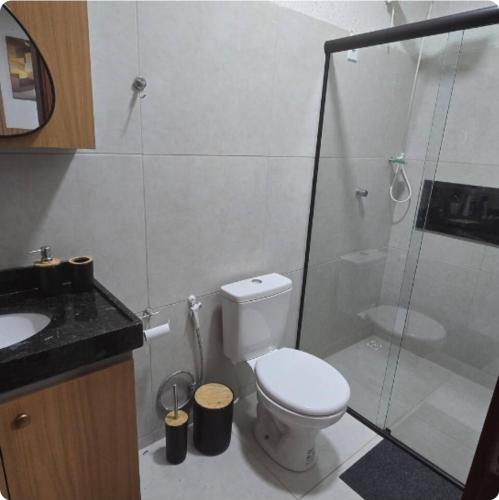 a bathroom with a toilet and a glass shower at Flat 11 Condomínio Ibiapaba Camocim in Camocim