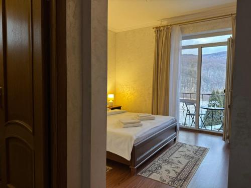 a bedroom with a bed and a window with a balcony at Садиба в горах in Solochyn