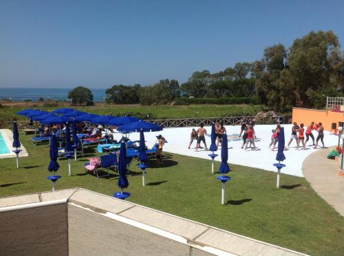 a group of people playing in a pool with blue umbrellas at Le Torri in Santa Marinella