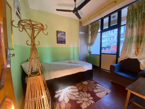 a bedroom with a bed and a chair and a window at Three Peaks Inn in Kathmandu