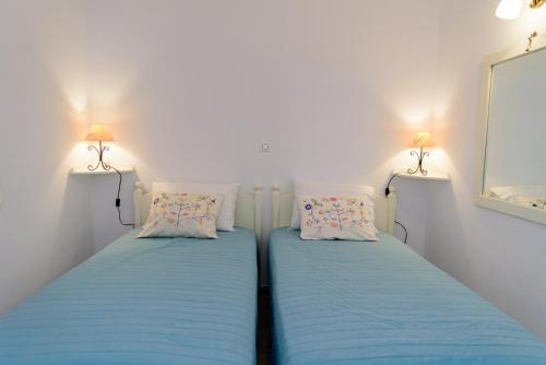 two beds in a small room with two lamps at Folia in Agia Marina