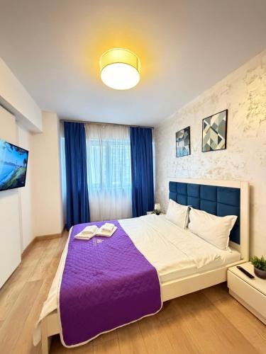 a bedroom with a large bed with purple sheets at Luxury Apartments Newton by GLAM - Parking Option in Iaşi
