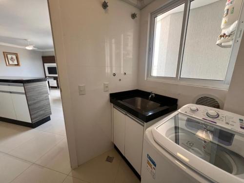 a kitchen with a sink and a dishwasher at Baía dos Golfinhos in Bombinhas