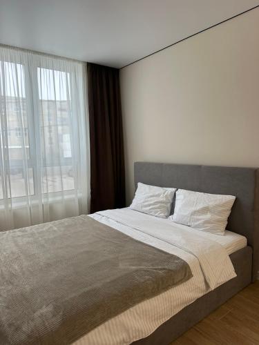 a bedroom with a large bed with a large window at ЖК Сонячна Тераса in Ternopil