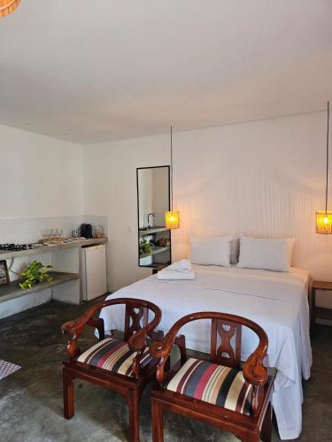 a bedroom with a large bed with two chairs at Casa Entre Coqueiros in Tamandaré