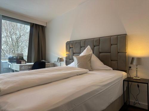 a bedroom with a large white bed with a large window at Hotel Unterfeldhaus in Erkrath