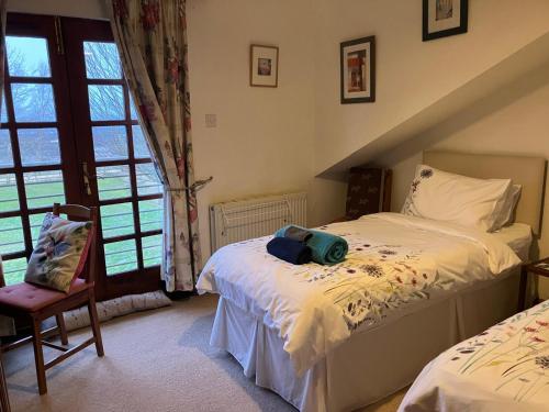 a bedroom with two beds and a chair and a window at Midkinleith Farm Holiday Cottage in Edinburgh