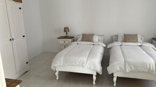 a white bedroom with two beds and a dresser at Apartment in Żebbuġ Malta in Ħal Muxi