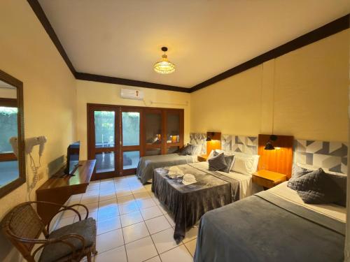een hotelkamer met twee bedden en een televisie bij Recanto Verde Praia Hotel Juquehy in Juquei