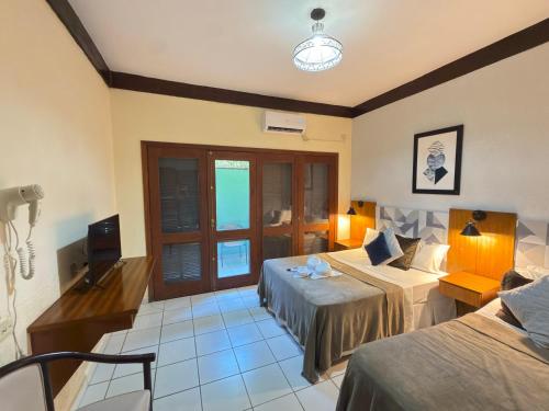 een hotelkamer met twee bedden en een televisie bij Recanto Verde Praia Hotel Juquehy in Juquei