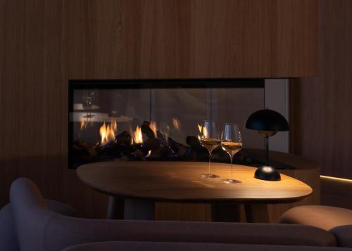 two wine glasses on a table in front of a fireplace at Boutique-Hôtel Le N3 par Champagne Thiénot in Reims