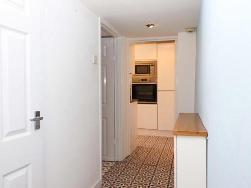 a hallway leading to a kitchen with a stove and microwave at Kenny cottage - 1 The Court in Dawlish
