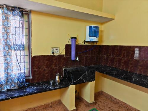 a bathroom with a sink and a tv on the wall at Nilan Aarudhra Homestay in Chidambaram