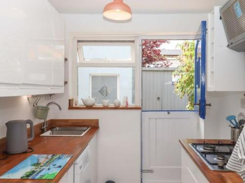 a kitchen with white cabinets and a window at Kenny cottage - 1 The Court in Dawlish