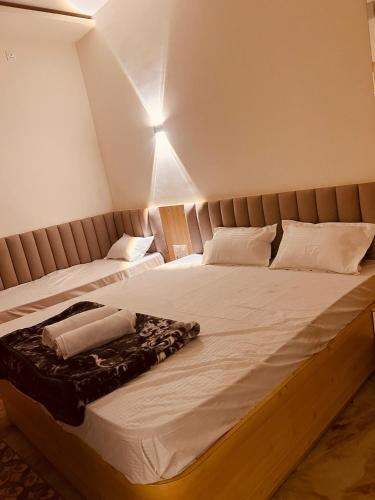 a bedroom with two beds with white sheets at Shree Guru Ashray in Ujjain