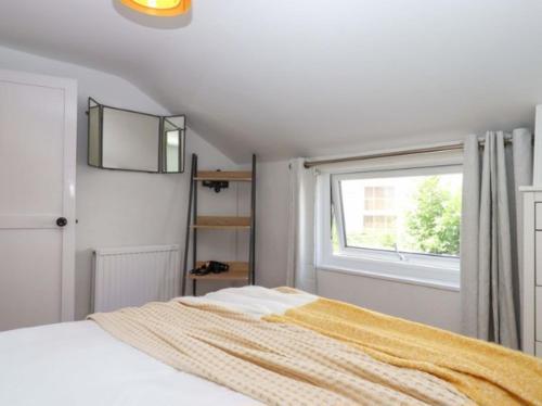 a white bedroom with a bed and a window at Kenny cottage - 1 The Court in Dawlish