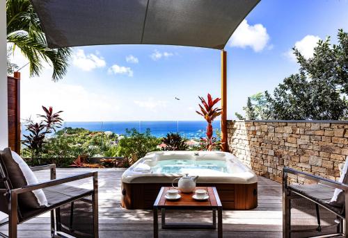 a hot tub on a patio with two chairs and a table at Tropical heaven in Les Trois-Îlets