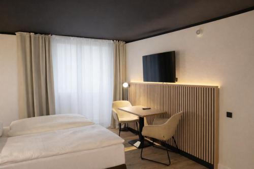 a hotel room with a bed and a table and chairs at BEELiving Augsburg in Augsburg