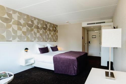 a hotel room with a bed and a lamp at Van Der Valk Hotel Rotterdam Nieuwerkerk in Nieuwerkerk aan den IJssel