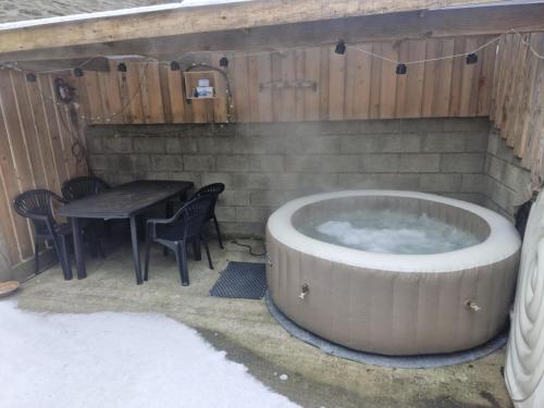 a hot tub in a patio with a table and chairs at les quatres sources in Houffalize
