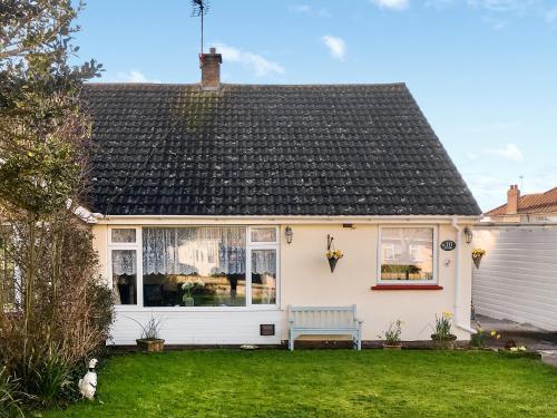 a white house with a bench in the yard at The Hollies in Weston-super-Mare