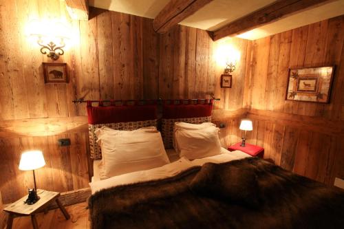 a bedroom with a bed with wooden walls and two lamps at Au Coeur Des Neiges Resort SPA & FREE E-BIKE in Courmayeur