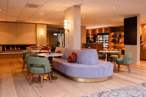 a lobby with a couch and tables and chairs at Van Der Valk Hotel Rotterdam Nieuwerkerk in Nieuwerkerk aan den IJssel