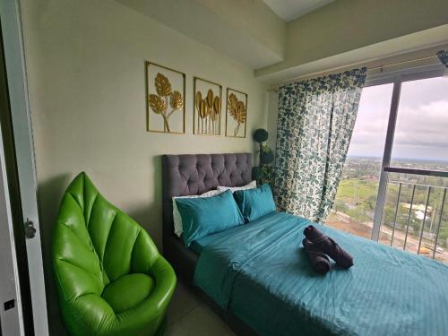 a bedroom with a bed and a green chair at Escapade in Tagaytay by JV in Kaybagal