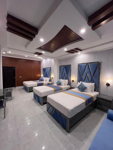 a hotel room with three beds and a television at Gulberg Residency Hotel in Lahore
