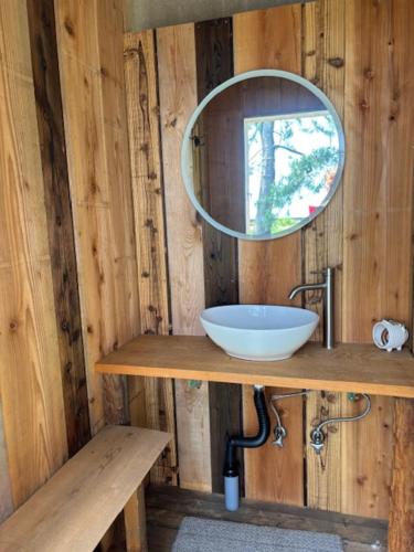 a bathroom with a sink and a mirror on a wooden wall at Kanzaki Beach House in Kanzaki
