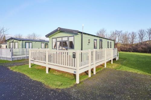 a green house with a porch and a fence at Host and Stay - 421 Wooler Park in Wooler