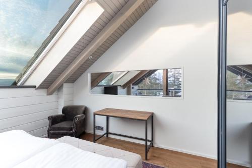 a bedroom with a bed and a desk and windows at Naava Chalet 401 Penthouse - Järvinäköala ilta-aurinkoon in Ähtäri