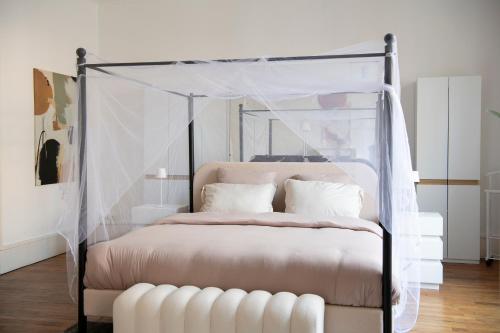 a bedroom with a canopy bed with white pillows at Le Saint-Quentin - Studio avec Terrasse in Saint-Quentin