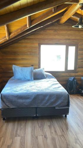 a bed in a room with a wooden wall at Cabañas Betsaida in Lago Meliquina