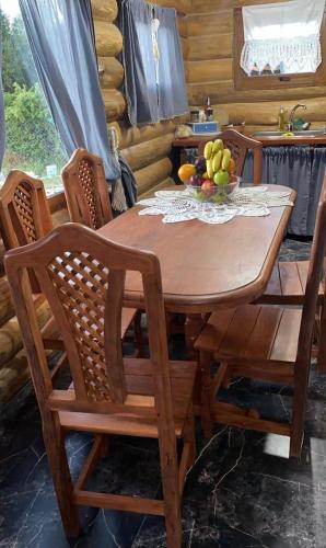 a wooden table with chairs and a bowl of fruit on it at Cabañas Betsaida in Lago Meliquina