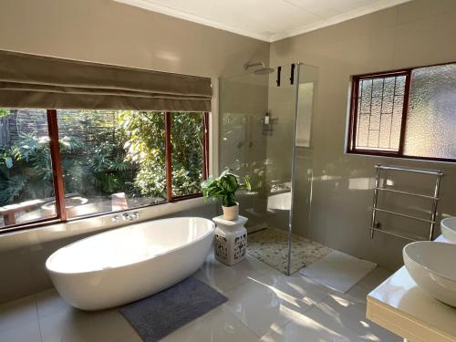 a bathroom with a large white tub and a sink at Ndlovu Addo River Lodge in Kirkwood