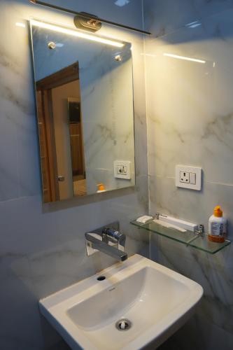 a bathroom with a white sink and a mirror at Yatindra Ashraya in Etāwah