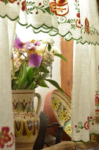 a vase with flowers in it next to a window at Dykyi Khutir in Melʼniki