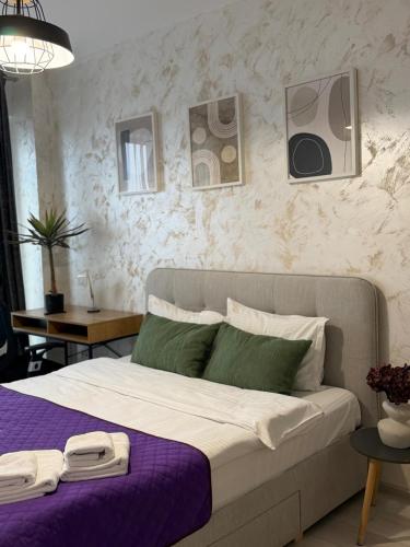 a bedroom with a large bed with a purple blanket at Studios Palas by GLAM Center Area and Mall - Parking Option in Iaşi