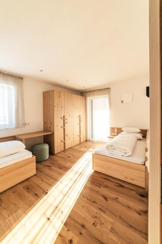 two beds in a room with wooden floors at Residence Louise in Vipiteno