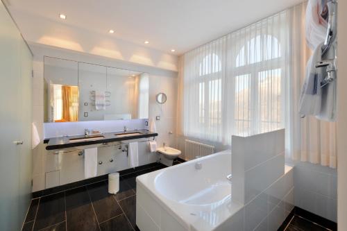 een witte badkamer met een bad en een wastafel bij Hotel Waldhaus Sils in Sils Maria