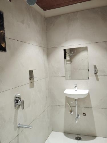 a white bathroom with a sink and a mirror at Kubo by Convivial Hotels in Raipur